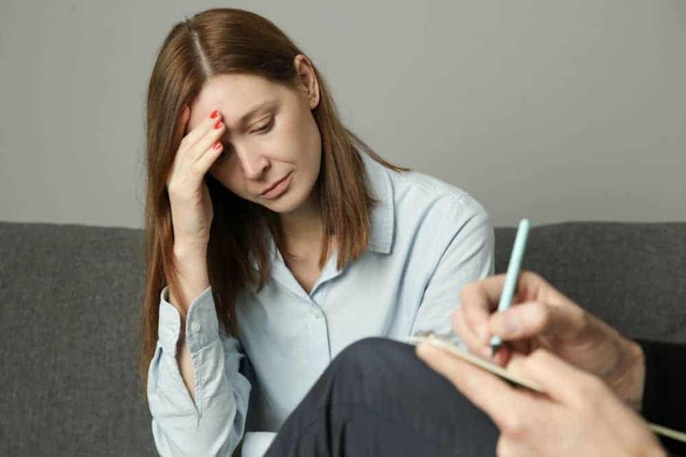 a woman holding her head while listening to her therapist