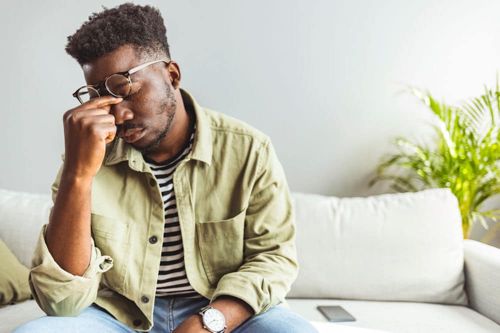 man pinching the bridge of his nose feeling stressed