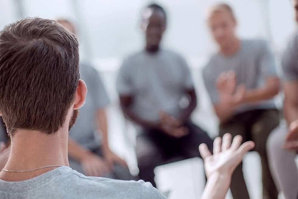 back of man's head as he shares with group during therapy session