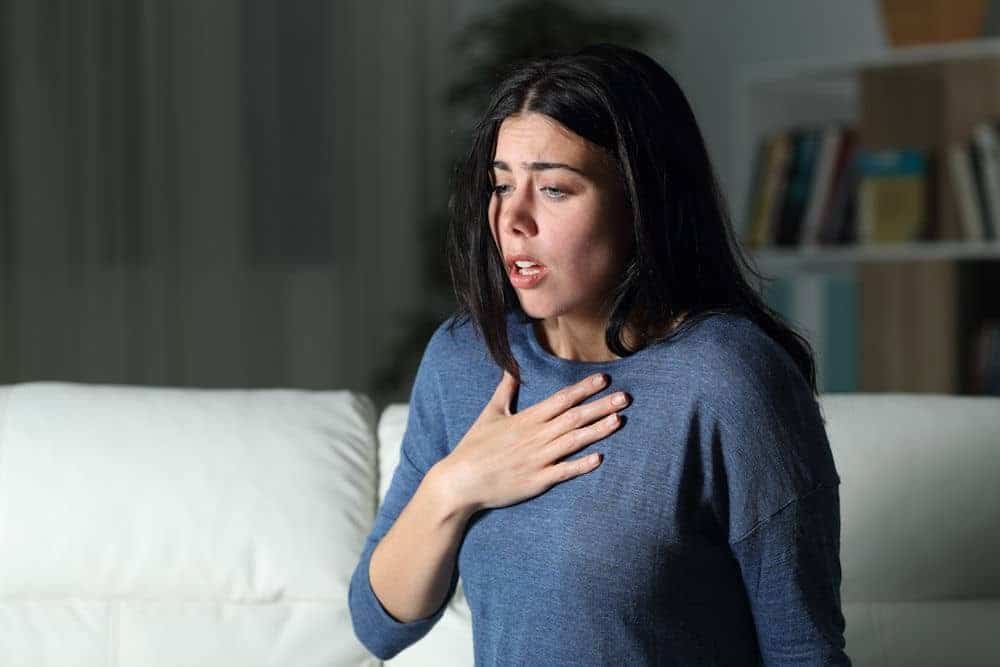woman with her hand on her chest experiencing panic level anxiety