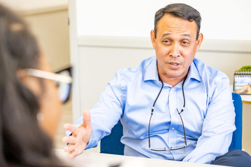 Person in a blue shirt speaking and gesturing.