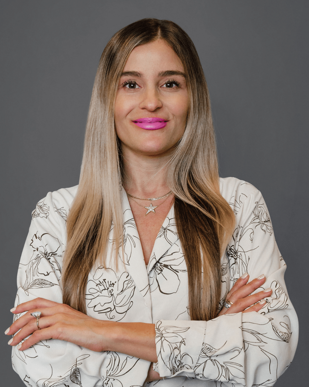 Person wearing floral print shirt with crossed arms.