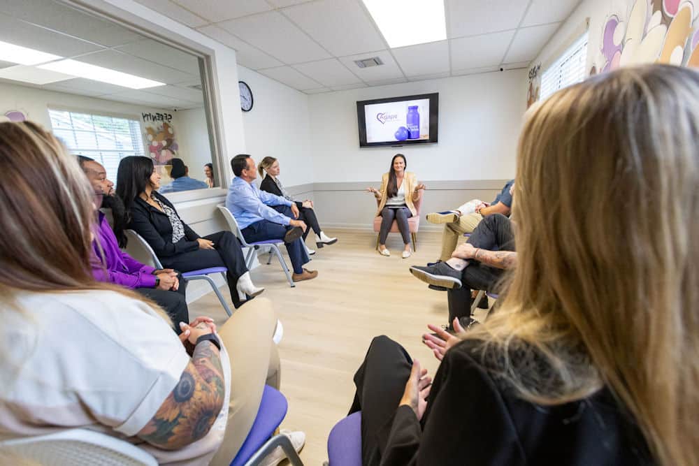 Person leading group therapy session seated in circle.