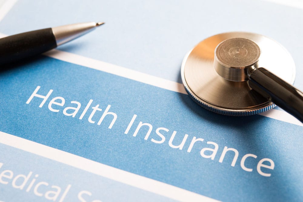 Health insurance document with pen and stethoscope on blue background.