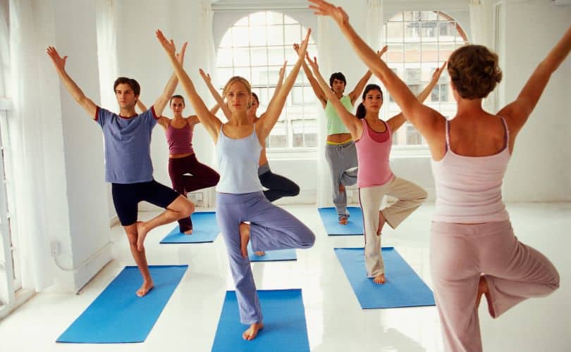 People practicing yoga in a studio wearing workout clothes.