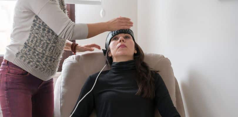 Person receiving therapy in a black turtleneck sitting on a chair.