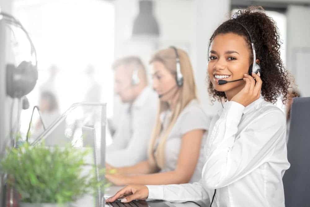 Person wearing headset and white shirt smiling in call center.