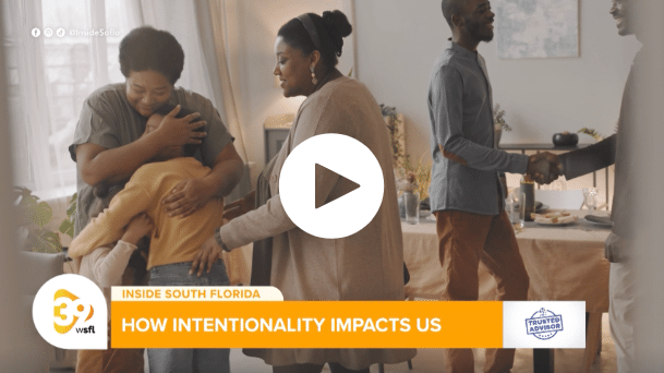 Person hugging child, another person shaking hands, table with decor in background.