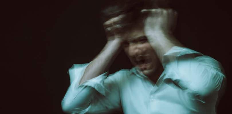 Person in a green shirt holding head in distress.