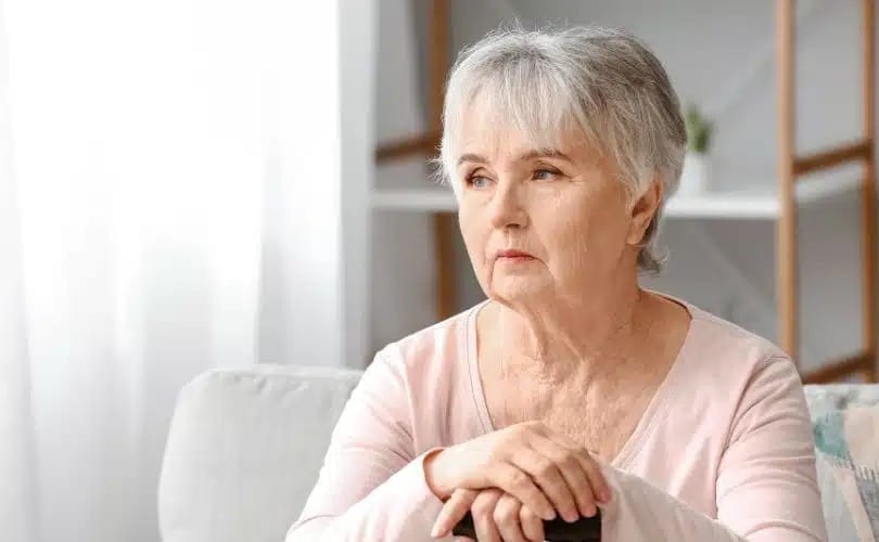 Person sitting in a light pink top, looking thoughtful.