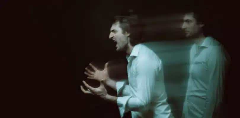 Person in white shirt with motion blur effect appearing to shout.