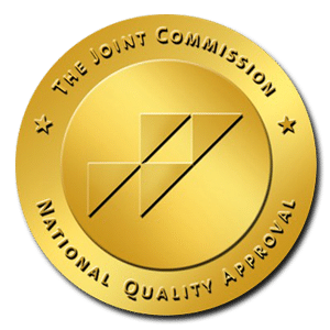 The Joint Commission gold seal of approval with geometric design.